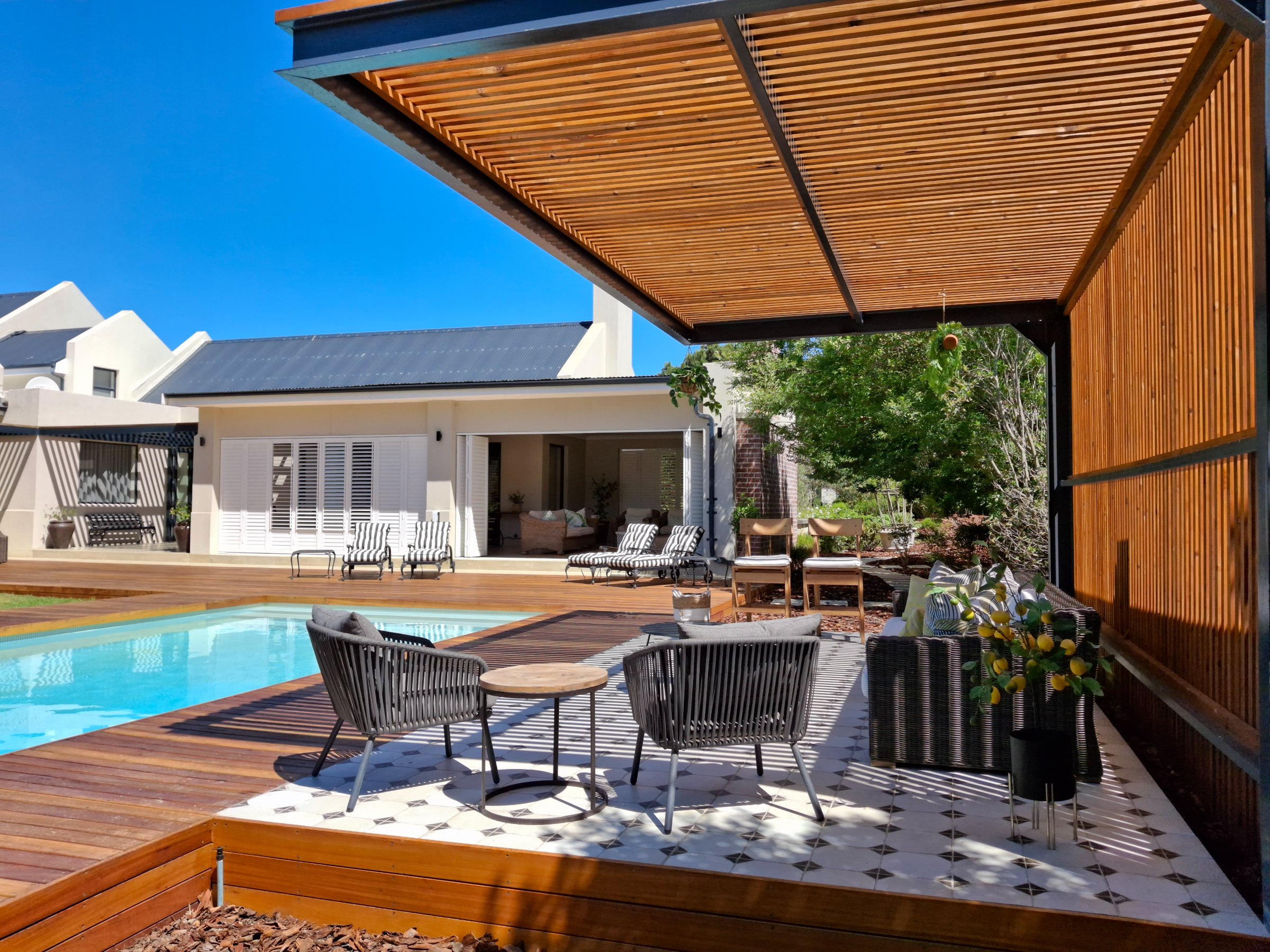 Timber slatted pergola over a pool deck patio